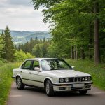 BMW E30 sur une route pittoresque, symbole d'une époque automobile emblématique.