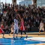 Match de basketball à Monaco avec des joueurs en action et des supporters passionnés.
